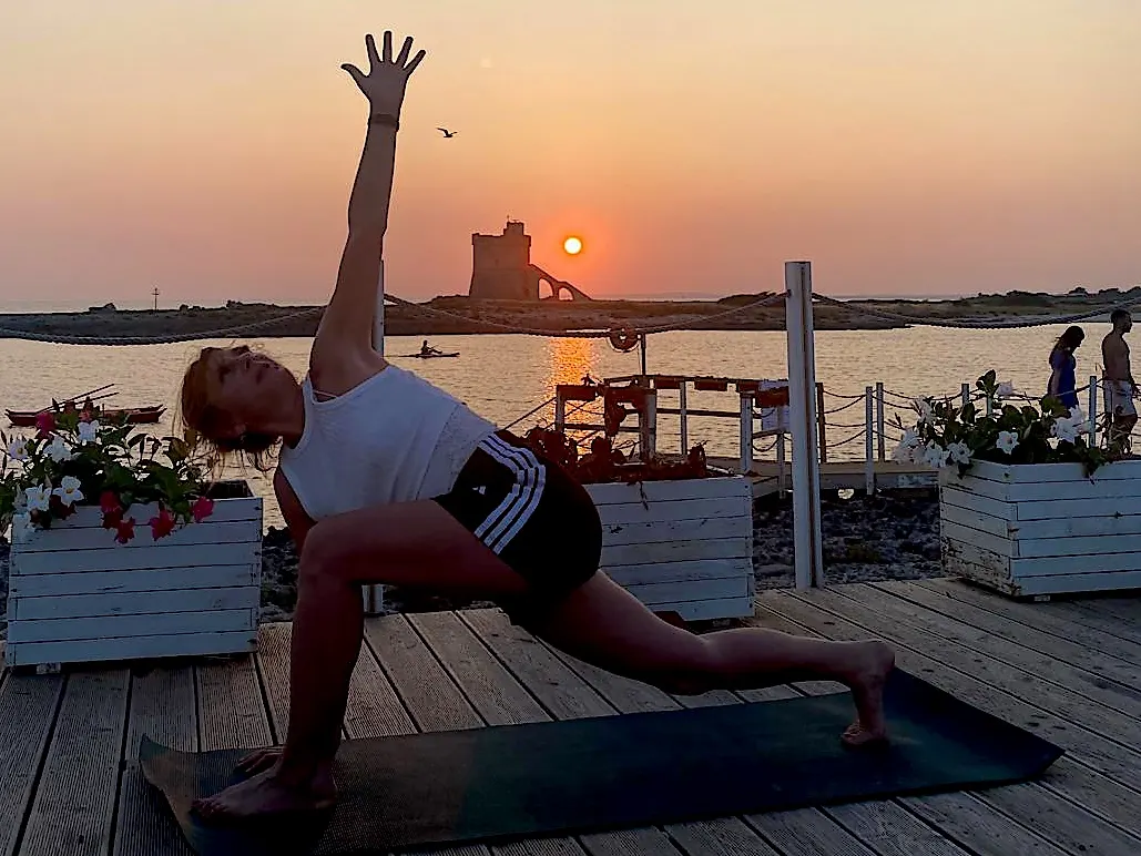 Sonia im gedrehten Seitwinkel auf der Matte bei Sonnenuntergang am Meer